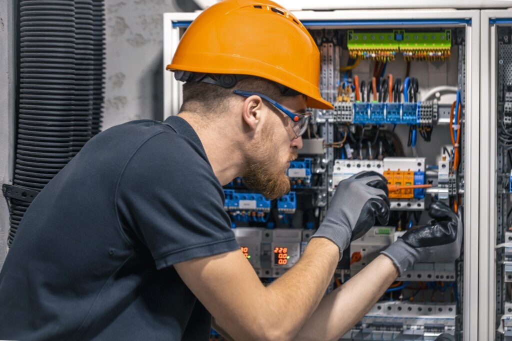 male electrician working switchboard with fuses